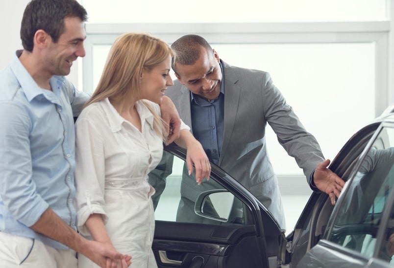 Verkäufer zeigt einem Paar ein Auto