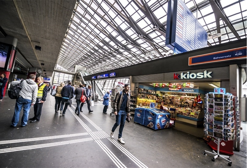 Vorbeilaufende Passanten am Kkiosk bei einem Bahnhof