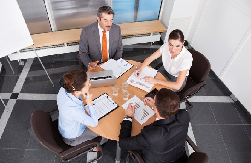 4 Personen besprechen Statistiken an einem Tisch