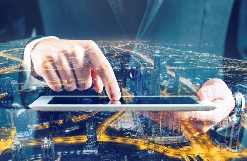 Mann mit Ipad in der Hand im Hintergrund eine Stadt bei Nacht