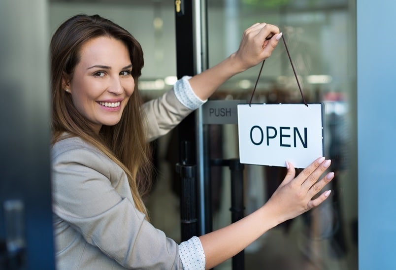 Frau hängt Open Schild an Türe