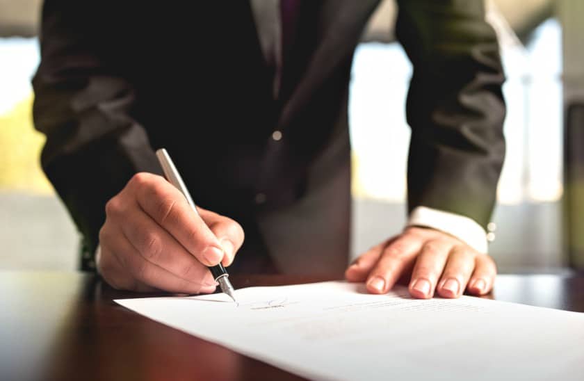 Mann am Unteeschreiben von einem Dokuments