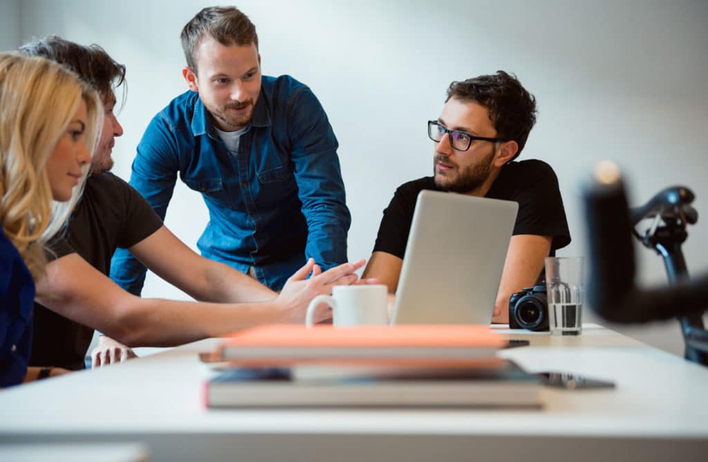 4 Personen besprechen etwas am Computer